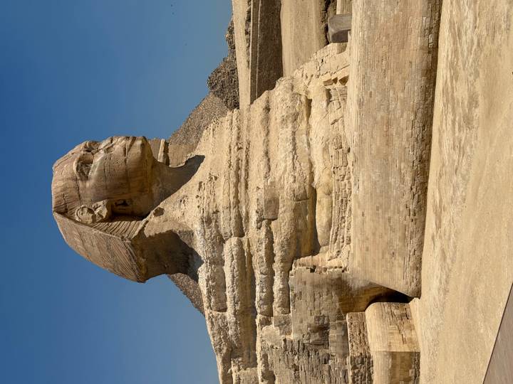 Iconic Great Sphinx of Giza with pyramid backdrop under clear blue sky.