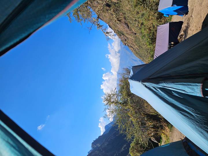Blue camping tent opening to clear sky and Andean landscape on the Inca Trail.