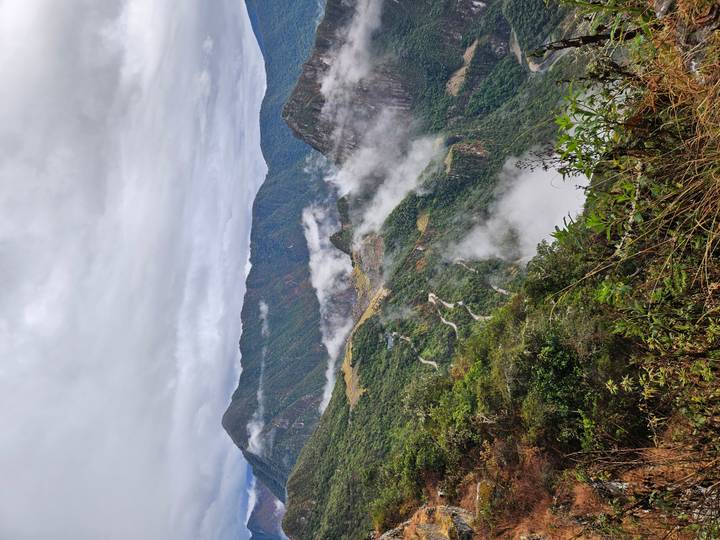 Clouds drifting through the verdant mountainsides and switchback road approaching Machu Picchu.