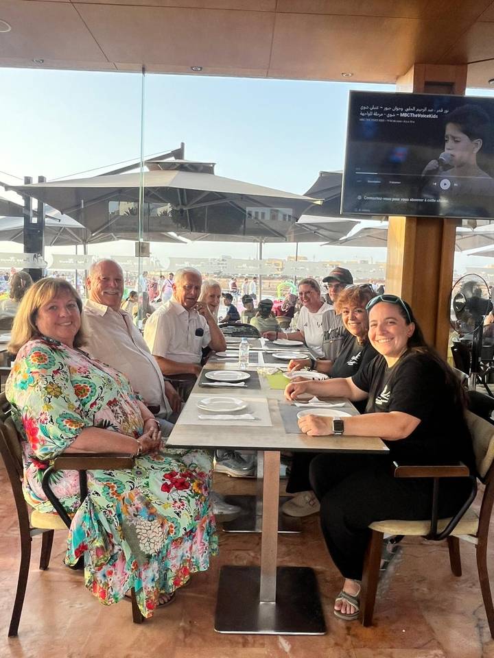 Tour group dining together at an open-air restaurant with busy plaza behind