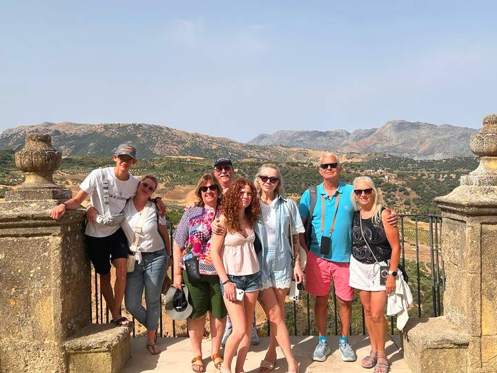 Family group posing at a stone viewpoint with rolling Andalusian hills behind