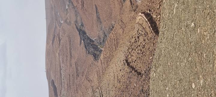 Layered, rocky desert hills with a deep eroded gully cutting through.