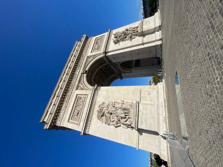 Grand Arc de Triomphe captured from below against a clear cobalt sky highlighting its carvings.