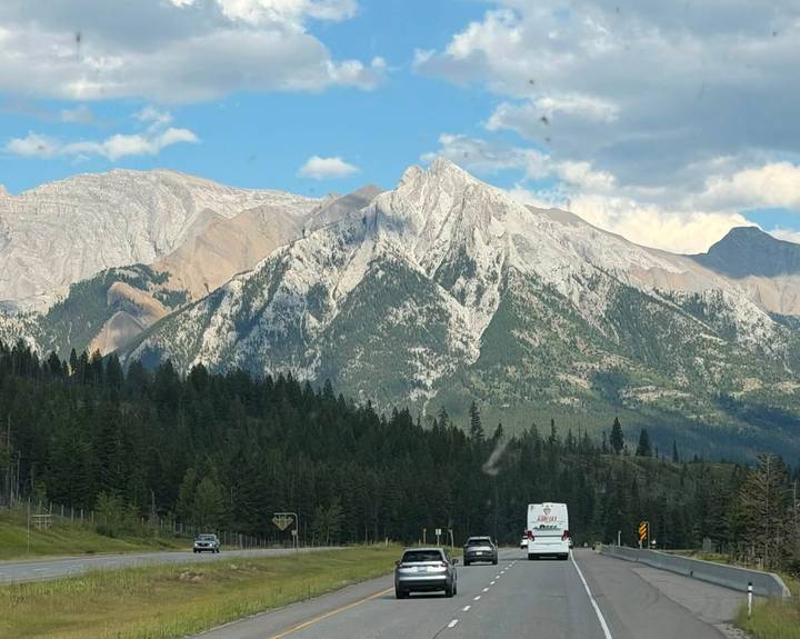 Rocky, jagged mountain peak rising above dense evergreen forest on a clear day.
