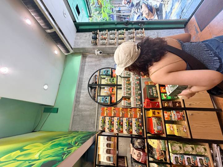 Inside a brightly stocked coffee souvenir shop, a woman in a cap browses shelves of packaged products.