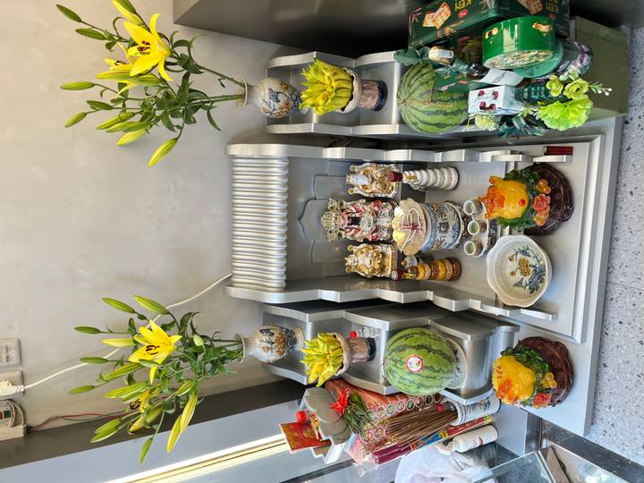 Intricate household altar adorned with offerings, flowers, and fruit inside a Vietnamese shop.