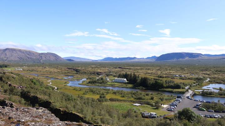 Expansive view over Thingvellir National Park rift valley with streams, church and parking area.