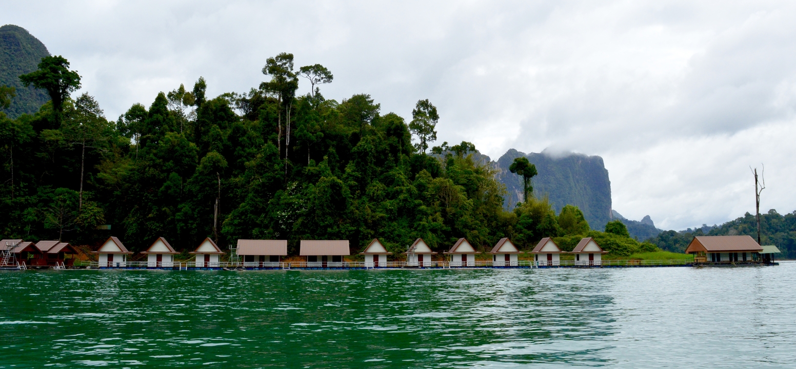 Floating bungalows on a lake with a forested backdrop.