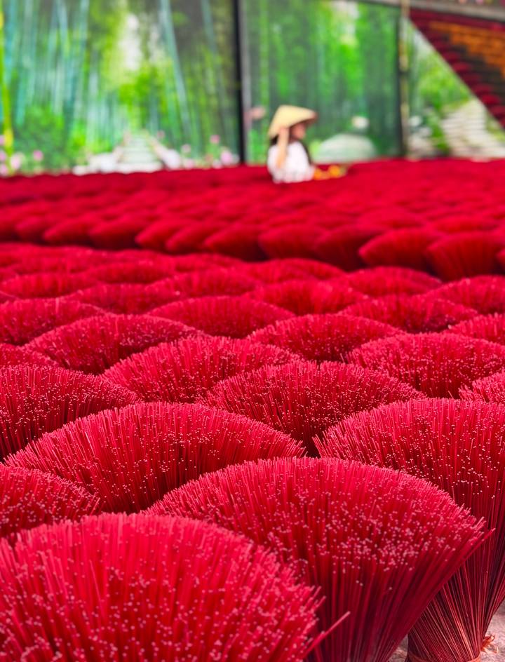 Close-up rows of bright red incense sticks bundled for drying create a vibrant pattern.