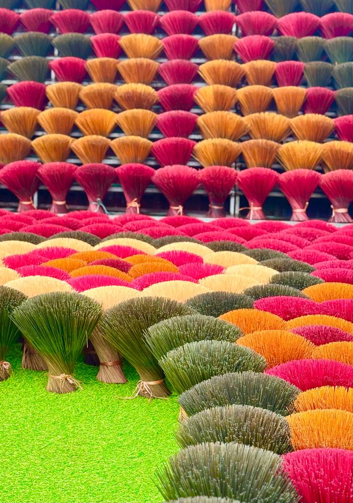 Multicolored fans of incense sticks displayed in rows, forming a rainbow of hues.