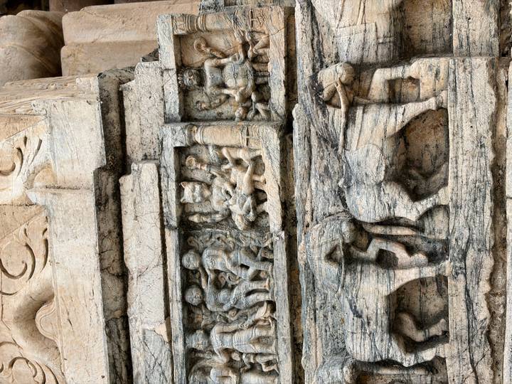 Close-up of intricate stone carvings featuring human figures and elephants on an ancient temple wall