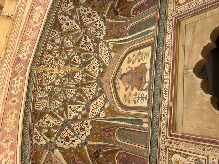 Ornately painted gateway with floral and geometric motifs and a deity fresco in a Rajput fort