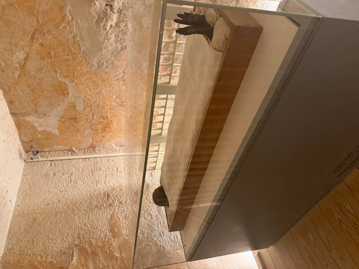 Glass-covered sarcophagus displayed in a dimly lit chamber with textured stone walls.