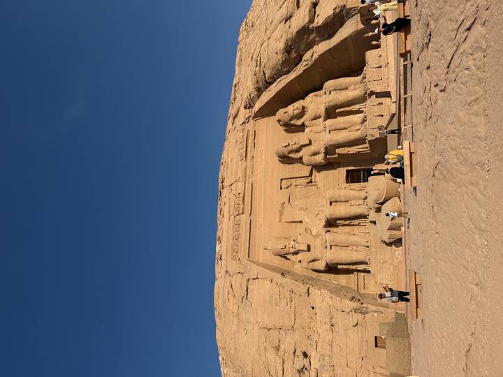 Great Temple of Abu Simbel carved into a sandstone cliff, statues illuminated by low morning sun.