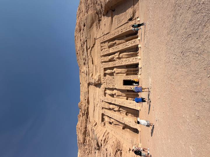 Smaller Abu Simbel temple facade with colossal figures and tourists approaching the entrance.
