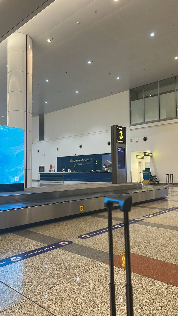 Vietnam Airlines baggage claim desk and carousel inside a modern airport terminal.