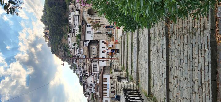 Cobblestone pathway leading through hillside village of white Ottoman-style houses with tourists strolling.