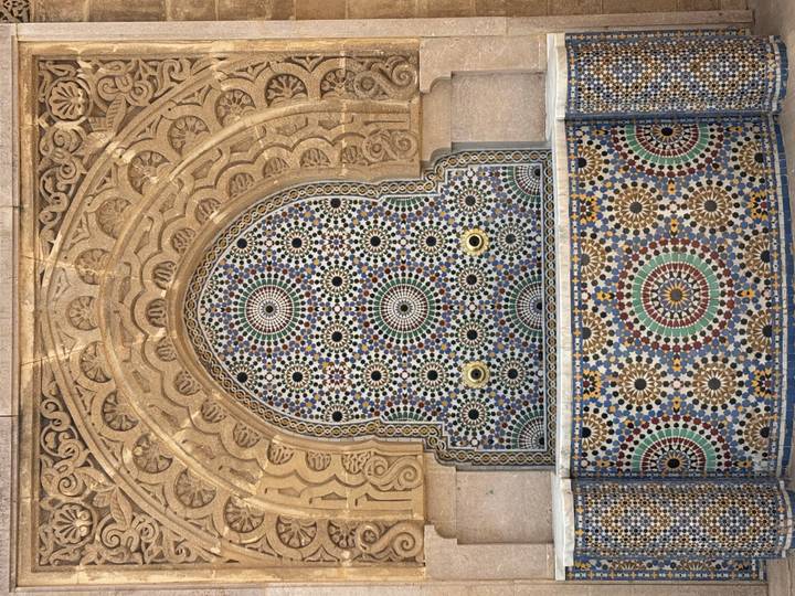 Colorful mosaic fountain set in an ornate carved stone archway.