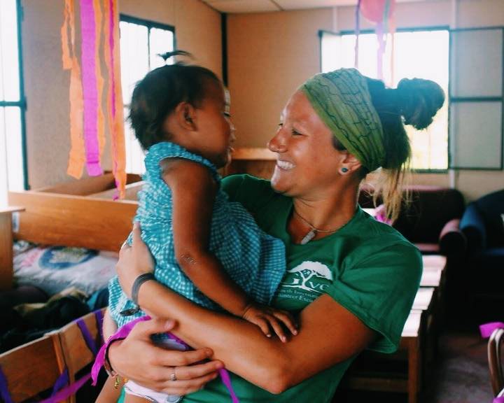 A woman holding a child, both smiling.