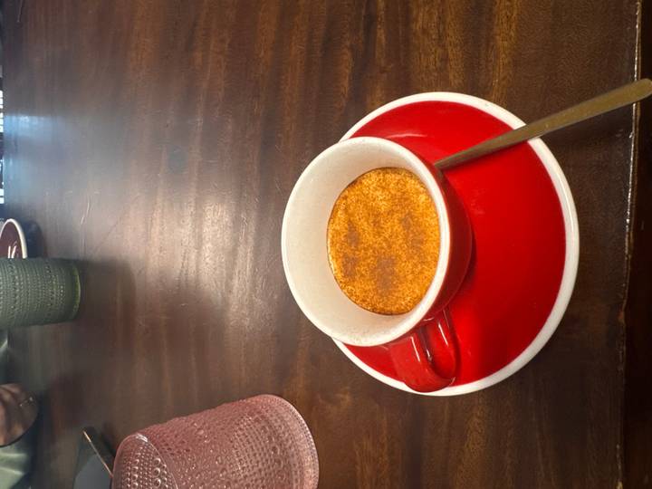 Close-up of a Vietnamese egg coffee served in red cup on wooden table.