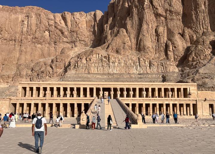 Grand façade of Hatshepsut’s Temple at Deir el-Bahri with tourists ascending the central ramp.