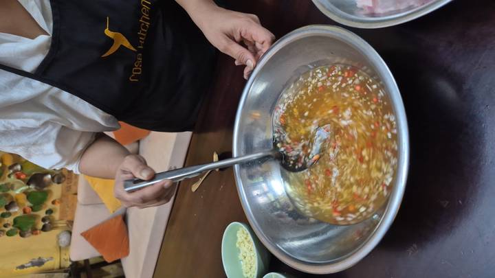 Cook stirs a bowl of Vietnamese dipping sauce flecked with red chili and garlic