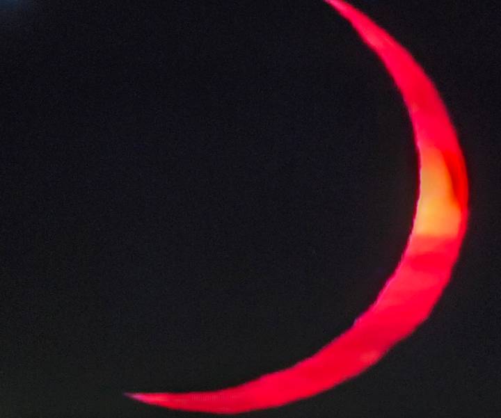 Blurry close-up of a red crescent shape against a black background.