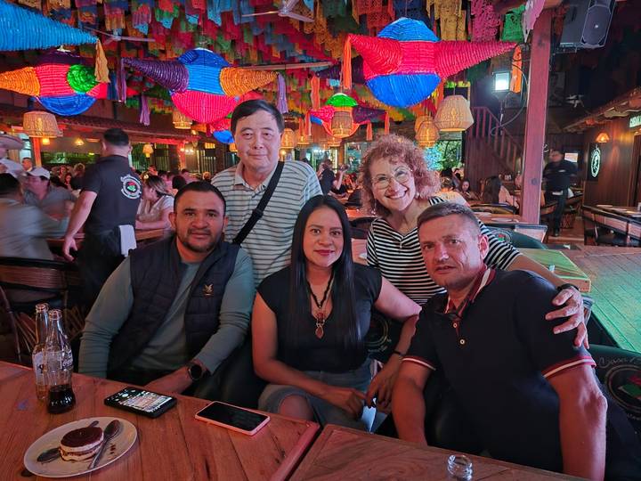 Friends seated at a busy, colorful lantern-filled restaurant.