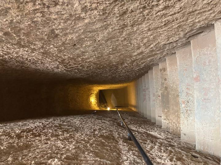 Narrow stone staircase descending into a softly lit tunnel inside an ancient structure.