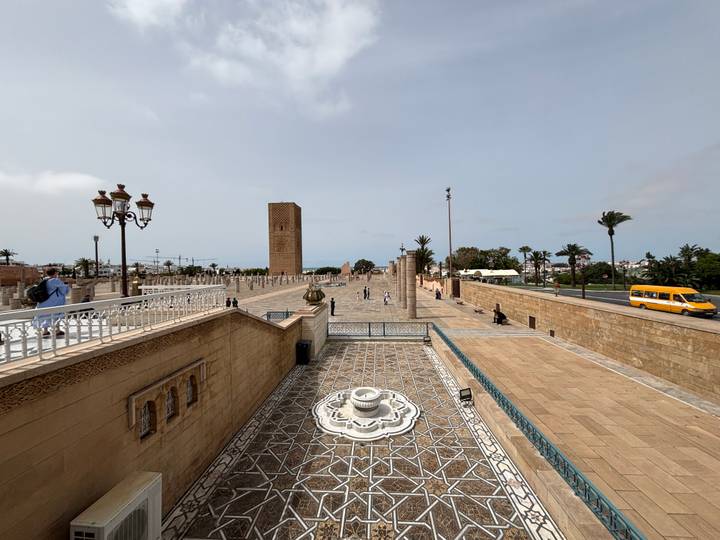 Wide plaza leading to Hassan Tower with fountains, palm-lined avenues and distant visitors exploring.