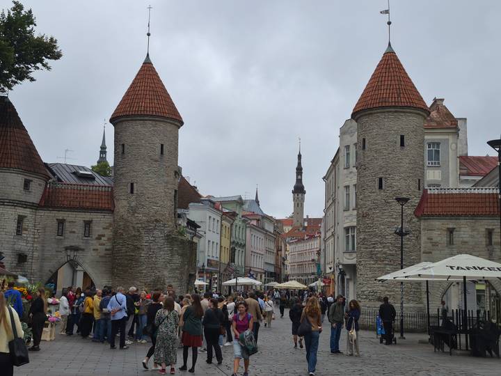 Crowds entering Tallinn’s medieval Viru Gate towers on a grey day.