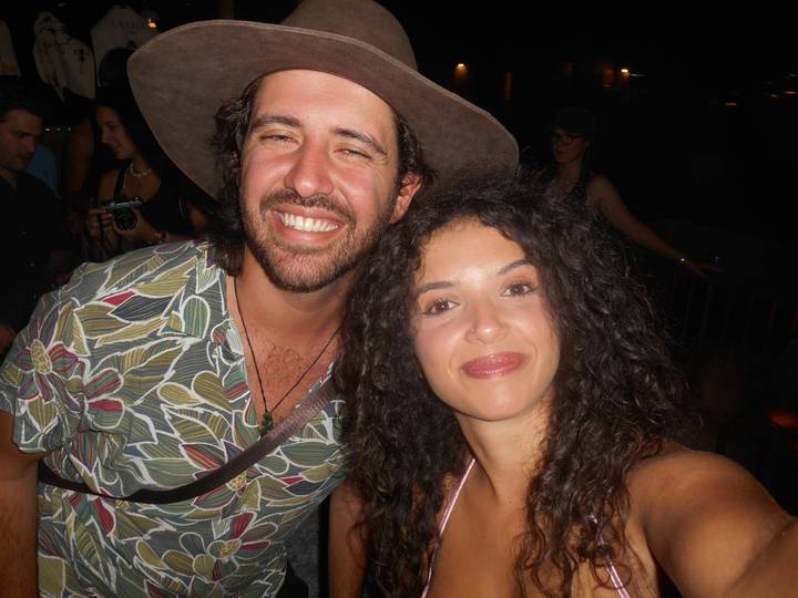 Smiling man and woman take a close-up flash selfie at night.