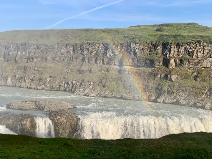 Powerful waterfall plunging into a rocky canyon with a vivid rainbow arching through the mist.