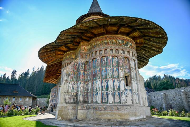 Apse of a painted monastery covered with rows of colourful saints and biblical scenes.