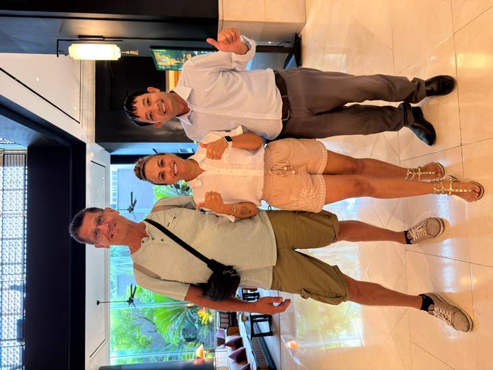 Guests posing with their tour guide in a hotel lobby, smiling and giving thumbs-up.