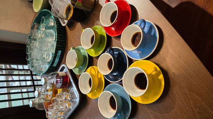 Colorful set of espresso cups with black coffee arranged on a wooden counter for a tasting session.