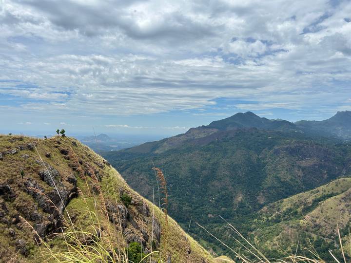 Expansive view over green mountains and valleys under a partly cloudy sky.