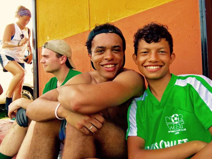 Two people smiling, seated against a painted wall.