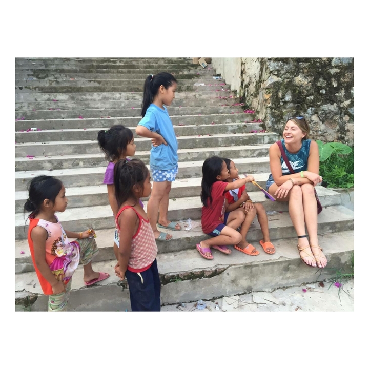 Woman sitting with children on stairs, engaging in conversation.