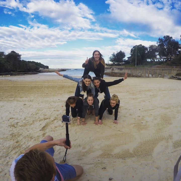 Group of young people forming a human pyramid on the beach.