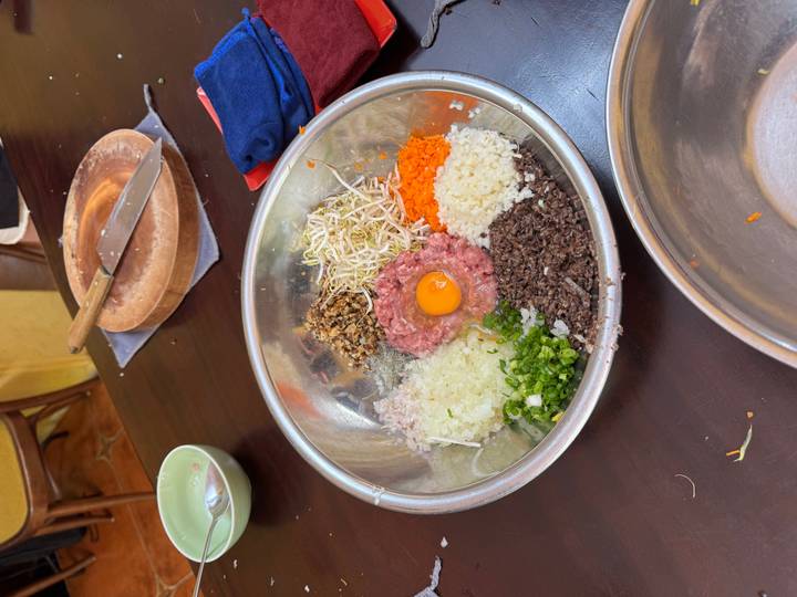 Metal bowl filled with minced pork, egg and chopped vegetables ready for mixing