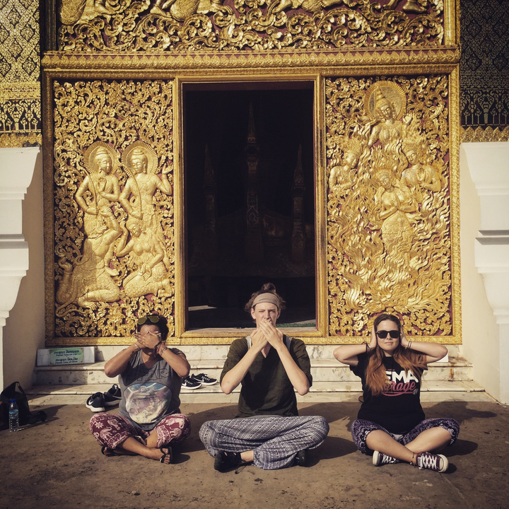Three people posing with a golden temple backdrop.