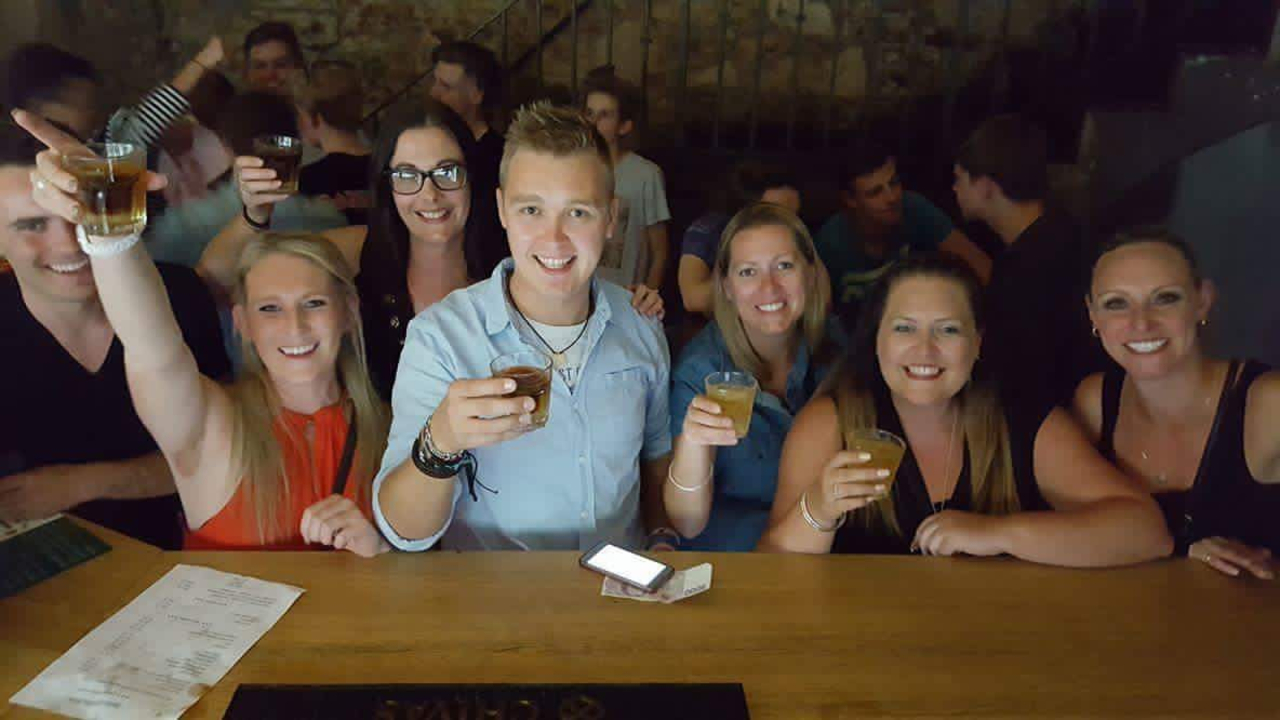 Group of people holding drinks in a bar setting.