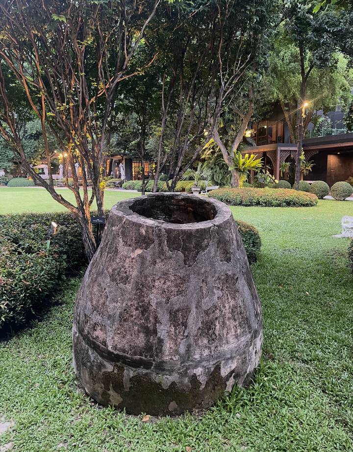 Ancient stone cistern set amid manicured lawns, shrubs and shady trees in a landscaped park.