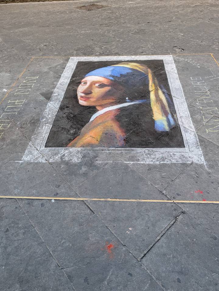 Street artist’s chalk rendition of Vermeer’s Girl with a Pearl Earring on stone pavement.