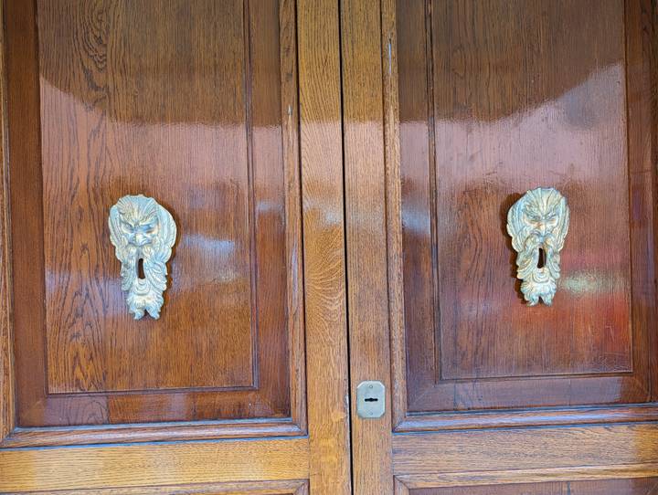 Polished wooden doors feature ornate brass lion-head keyhole plates.