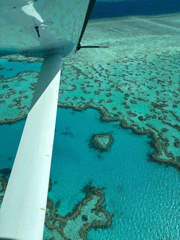 Aerial window view of turquoise coral formations including the famous heart-shaped reef in clear blue water.