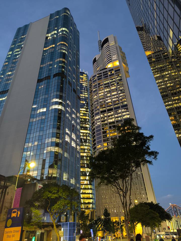 Modern high-rise office towers glow with interior lights at dusk against a deepening blue sky.