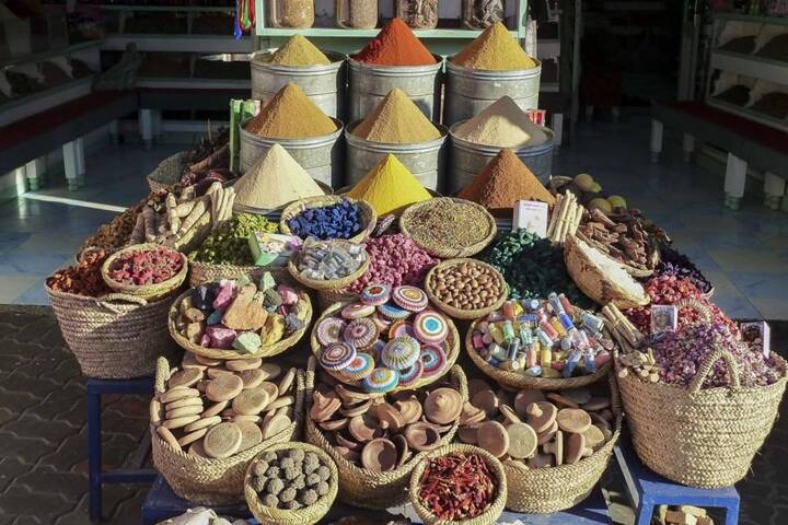 Vibrant display of multicoloured spices, dried flowers and local crafts neatly arranged in baskets at a Moroccan market stall.
