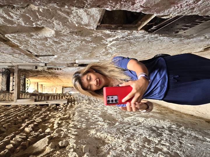 Woman snaps a selfie in a narrow, rough-plastered alley of an old medina.